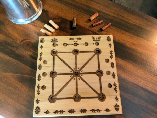 A wooden nature themed Three Men's Morris Board featuring acorns and pinecone motifs